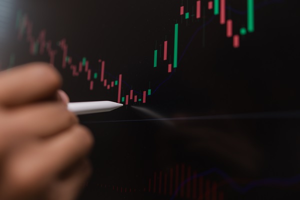 Professional trader analyzing stock market charts on laptop, tablet, and monitor while reviewing candlestick patterns, technical indicators, and market trends to support informed investment decisions.